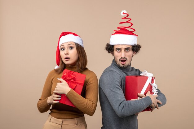 Top view of new year mood and party concept - surprised lovely couple holding gifts wearing santa claus hats