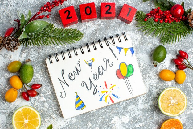 Top view new year written on notepad wood blocks cut lemons feijoas xmas ornaments on grey table
