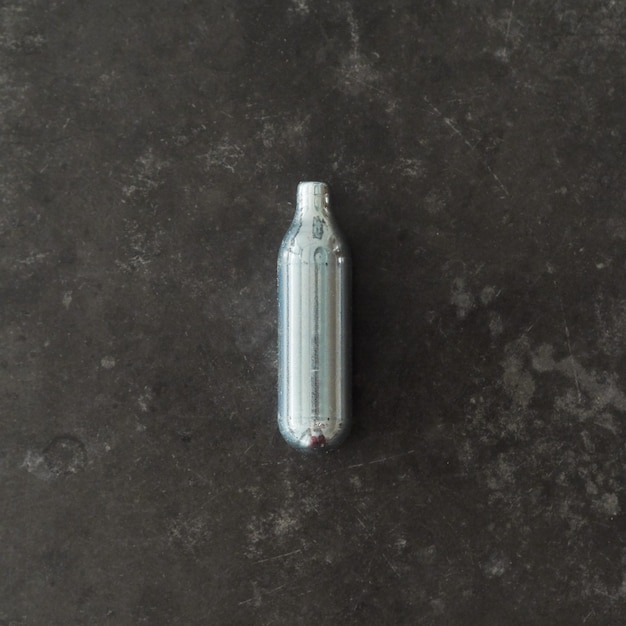 Free photo top view of a nitrous oxide capsule on a concrete surface