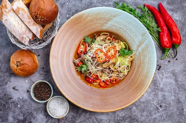 Top view of noodles with beef garnished, chili pepper onion and grated cheese