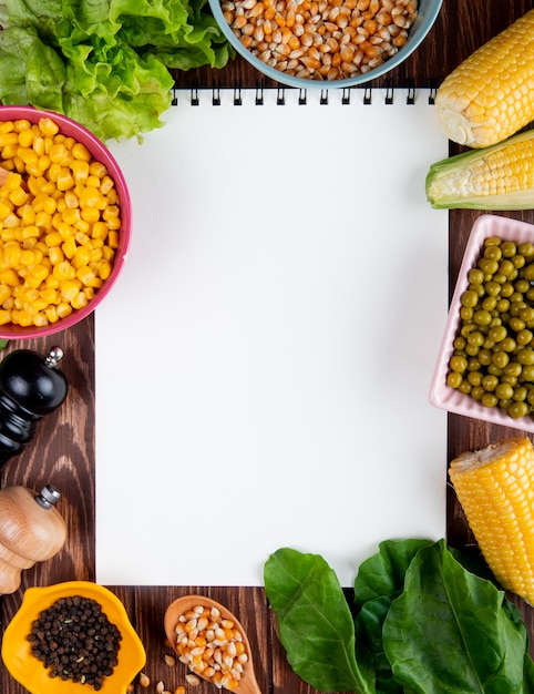 Top view of note pad with corn seeds lettuce spinach black pepper seeds green peas with copy space