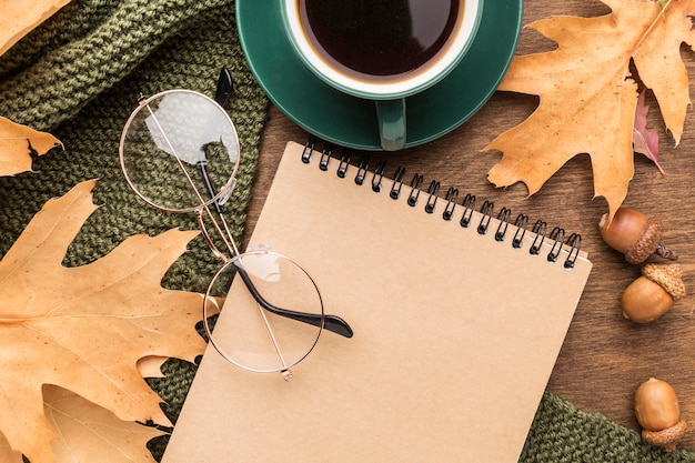 Top view of notebook and autumn leaves with glasses