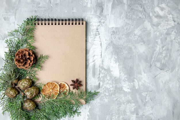 Top view notebook dried lemon slices anises pine tree branches on grey surface