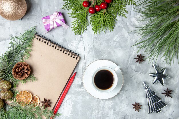 Top view notebook dried lemon slices anises pine tree branches red pencil cup of tea on grey surface