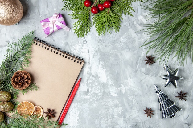 Top view notebook dried lemon slices anises pine tree branches red pencil xmas tree toys on grey background free space