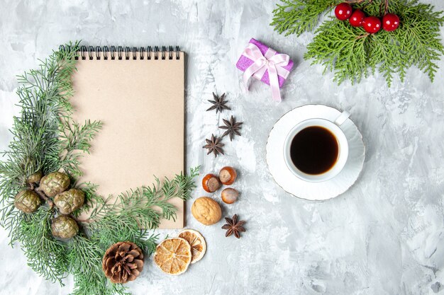 Top view notebook dried lemon slices anises pine tree branches walnut hazelnut cup of tea on grey surface