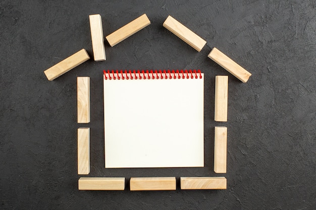 Top view notebook in house shaped wood blocks on black