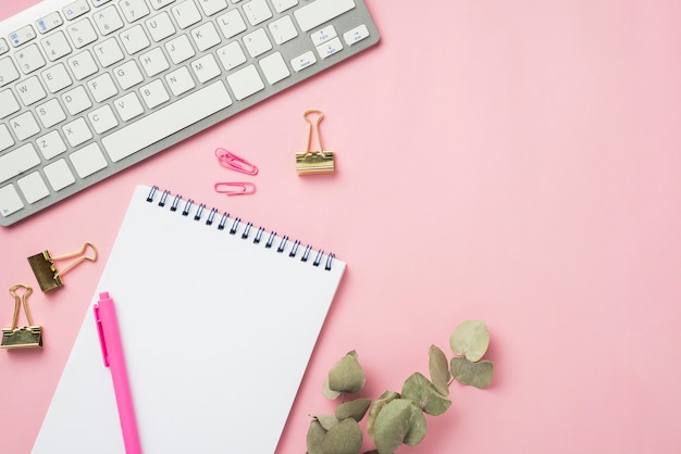 Top view of notebook and keyboard on desk with dried leaves