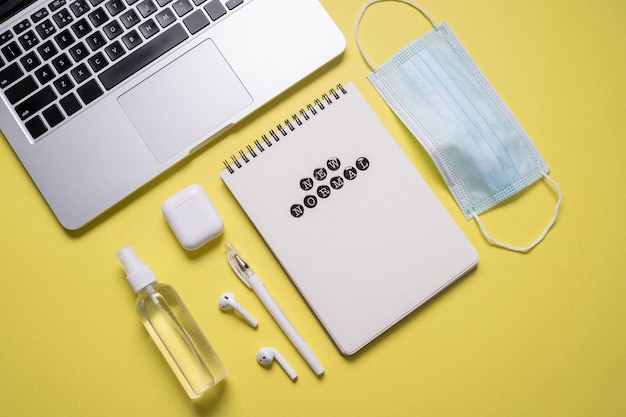 Top view of notebook next to medical mask with hand sanitizer