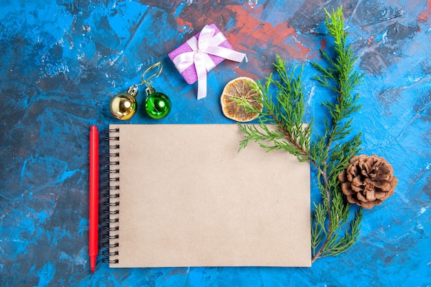 上面図ノートブック松の木の枝松ぼっくりクリスマス飾り青い背景に赤鉛筆