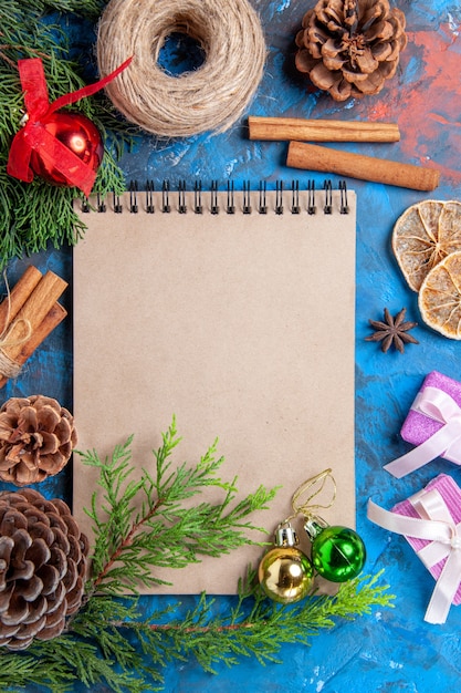 Top view a notebook pine tree branches pinecones star anises straw thread on blue background