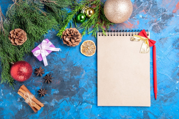 Free photo top view a notebook pine tree branches red pencil star anises on blue background