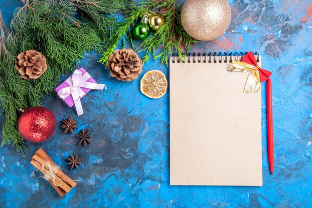 Top view a notebook pine tree branches red pencil star anises on blue background