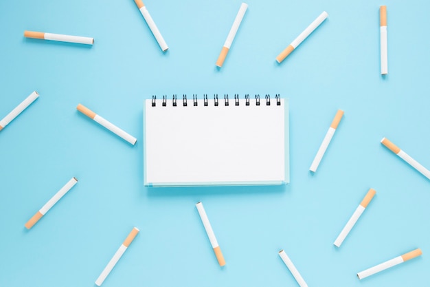 Top view notebook surrounded by cigarettes