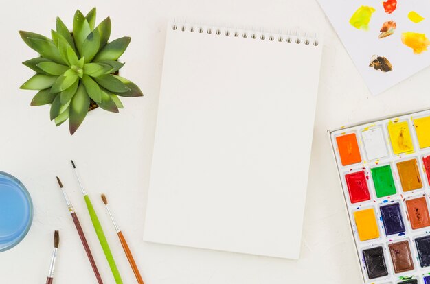 Top view notebook surrounded by painting elements