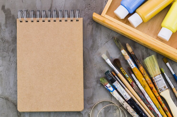 Free Photo top view notebook surrounded by painting elements