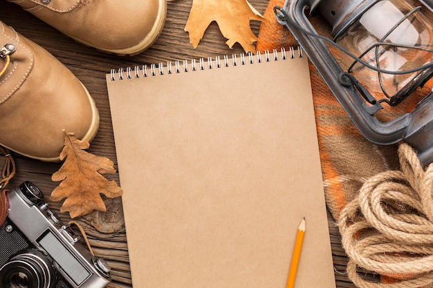 Top view of notebook with autumn leaves and boots