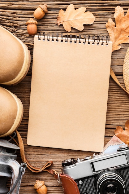 Top view of notebook with boots and autumn leaves