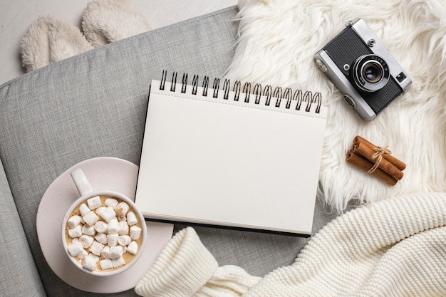 Top view of notebook with camera and cup of hot cocoa with marshmallows