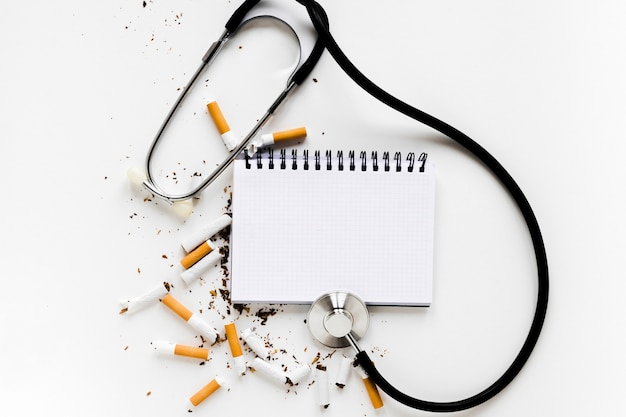 Free photo top view notebook with cigarettes and stethoscope