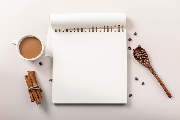 Top view of notebook with coffee cup and cinnamon sticks