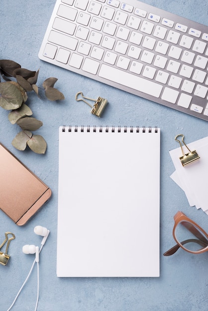 Top view of notebook with dried leaves and smartphone on desk