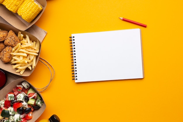 Top view notebook with food on yellow background