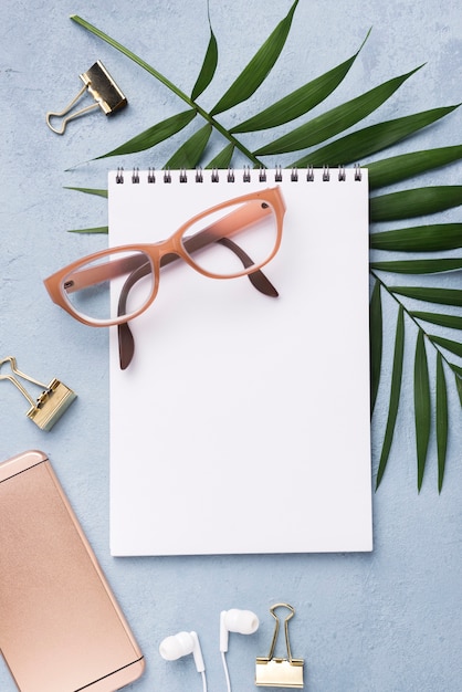 Top view of notebook with glasses and leaves on desk