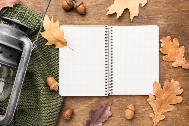 Top view of notebook with lantern and autumn leaves