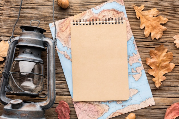 Top view of notebook with map and autumn leaves