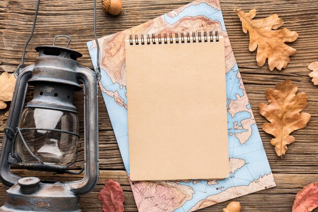 Top view of notebook with map and autumn leaves