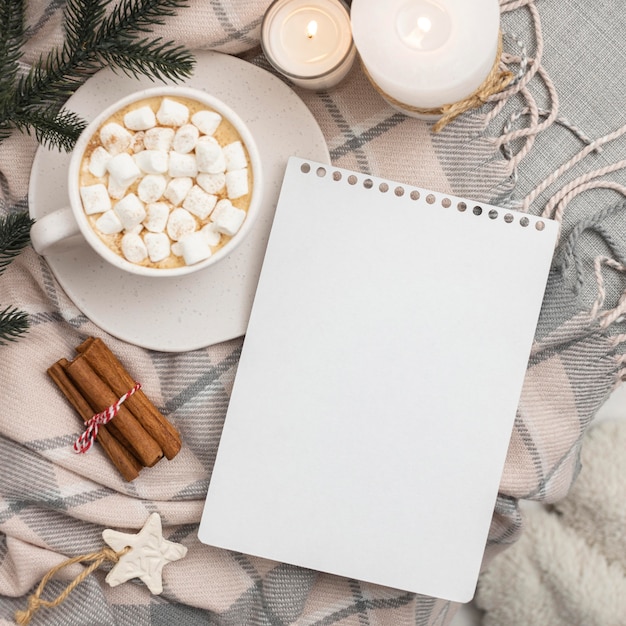 Top view of notebook with mug of marshmallows and cinnamon