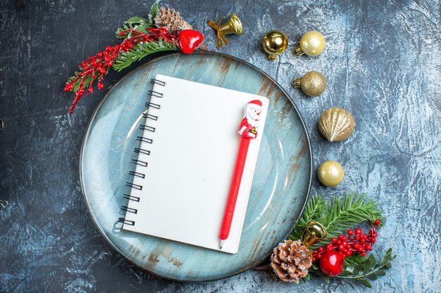 Top view of notebook with pen on blue plate decorative accessories on dark background