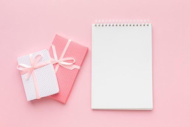 Top view of notebook with pink presents