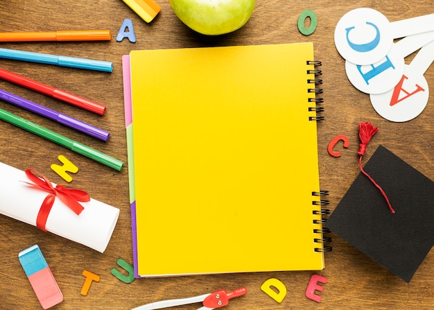 Top view of notebook with school supplies and diploma