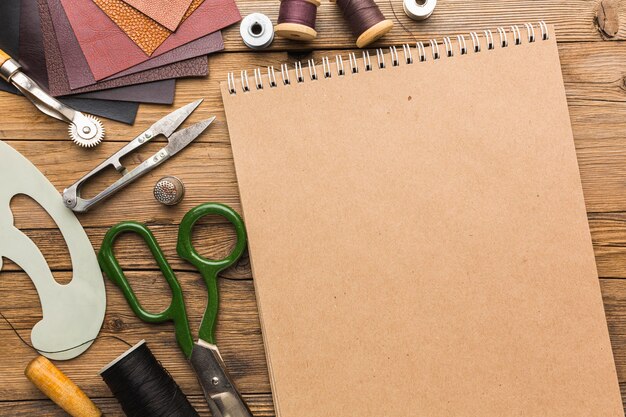 Top view of notebook with scissors and leather