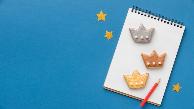 Free photo top view of notebook with three crowns and stars for epiphany day