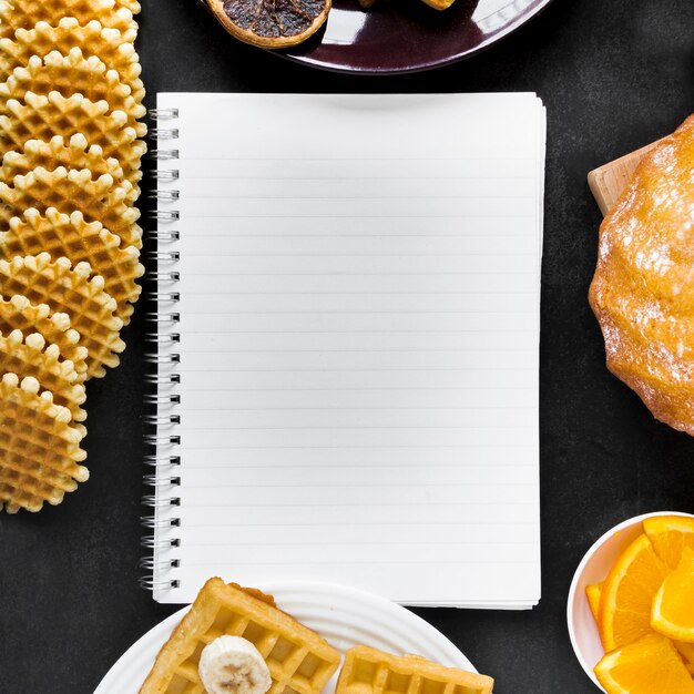 Top view of notebook with waffles and citrus