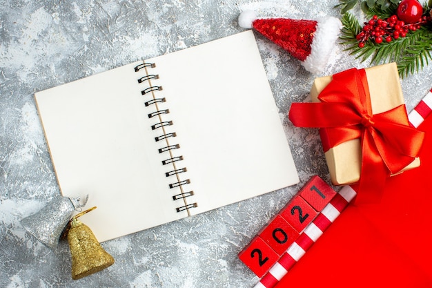 Top view notebook wood blocks small santa hat present xmas bells on grey white table