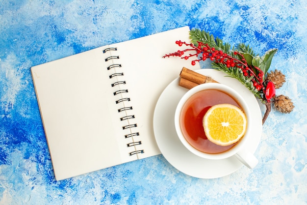 Top view notepad cup of tea xmas tree branch on blue table