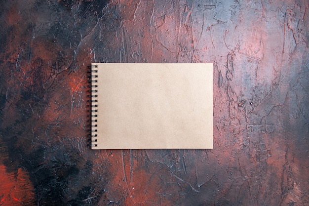 Top view a notepad on dark red table with copy place