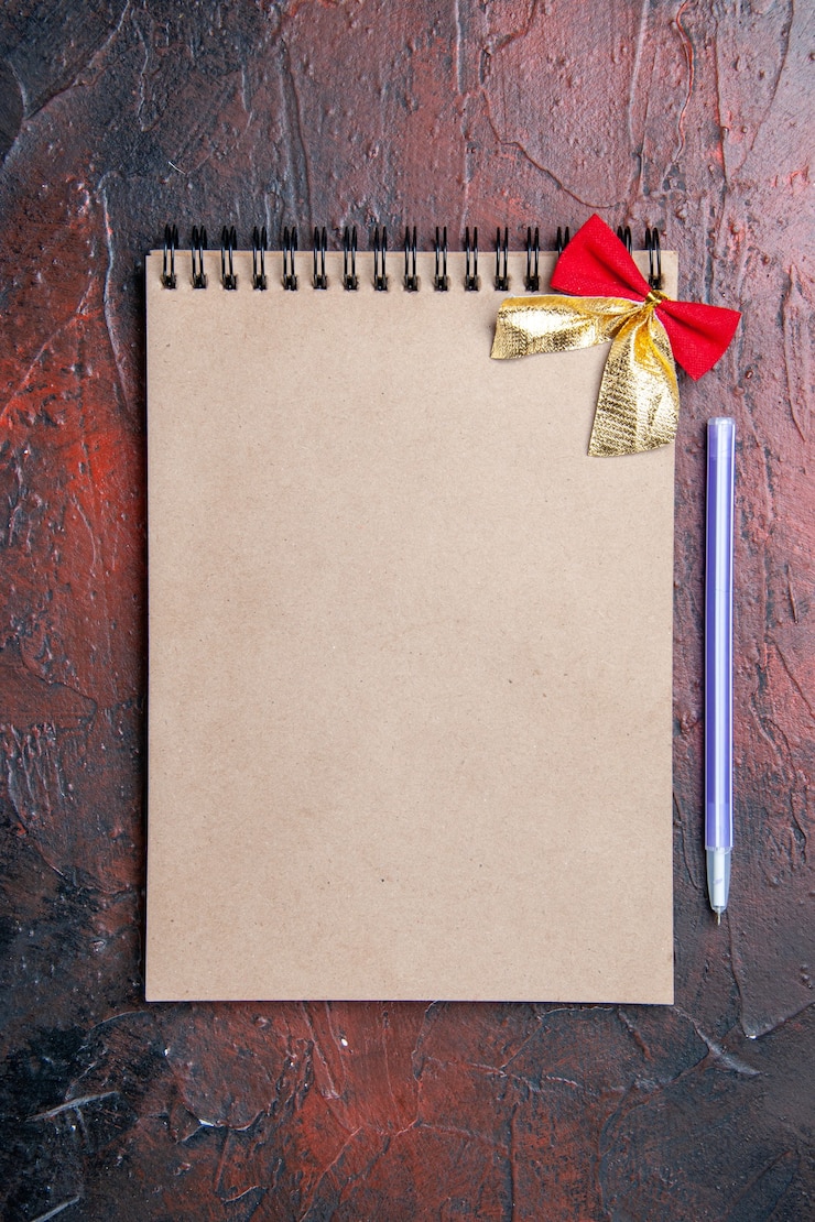 मुफ़्त फोटो top view a notepad with little bow pen on dark red table