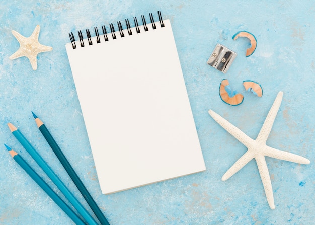 Top view notepad with pencils on blue background