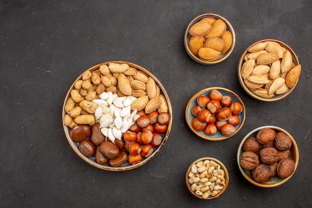 Top view of nut composition fresh nuts inside pots on dark surface