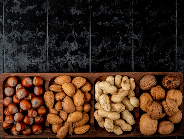 Top view of nut mix hazelnuts almond and peanuts in shell on black background with copy space