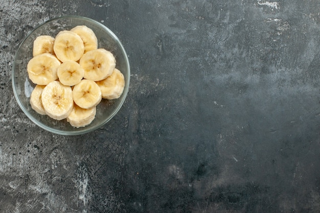灰色の背景にガラスの鍋ナイフで刻んだ上面の栄養源新鮮なバナナ