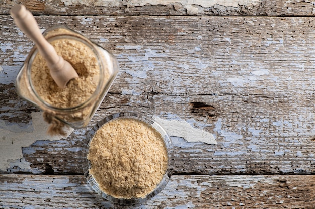 Top view nutritional yeast in flakes in glass jars on rustic wooden background