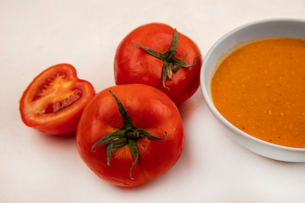 白い壁にトマトを分離したボウルに栄養価の高いレンズ豆のスープの上面図