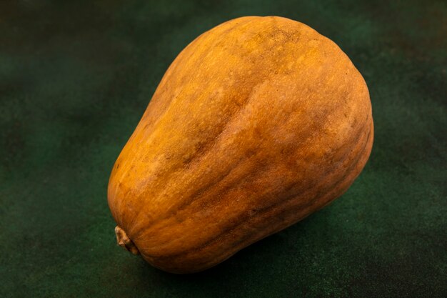 Top view of a nutritious orange vegetable pumpkin isolated on a green surface