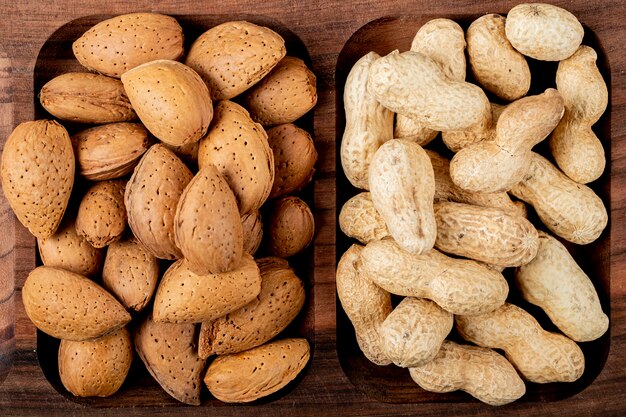 Top view of nuts almonds with peanuts in shell on a wooden tray